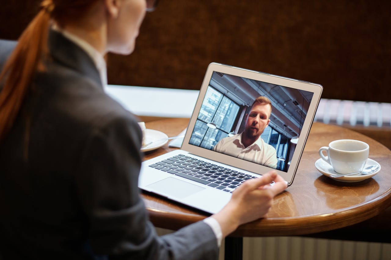 A businesswoman in a cafe using a laptop for an online video conference call.